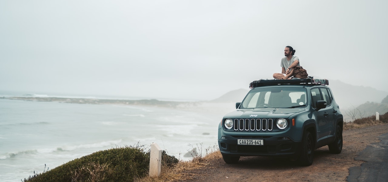 man sitting near ocean cliff on top of his Jeep Renegade - Rocket Chip plug in performance chips