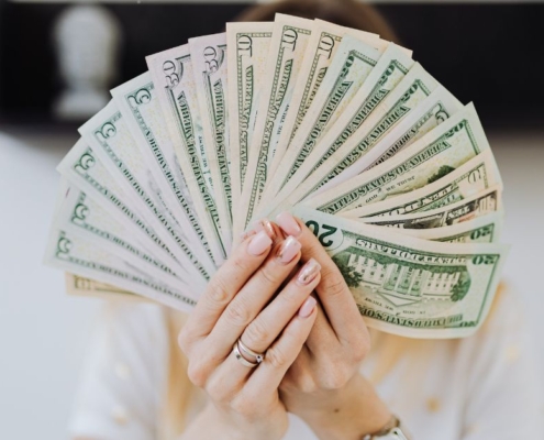 woman holding up a fan of USD paper currency - rocket chip ECU tuning chip