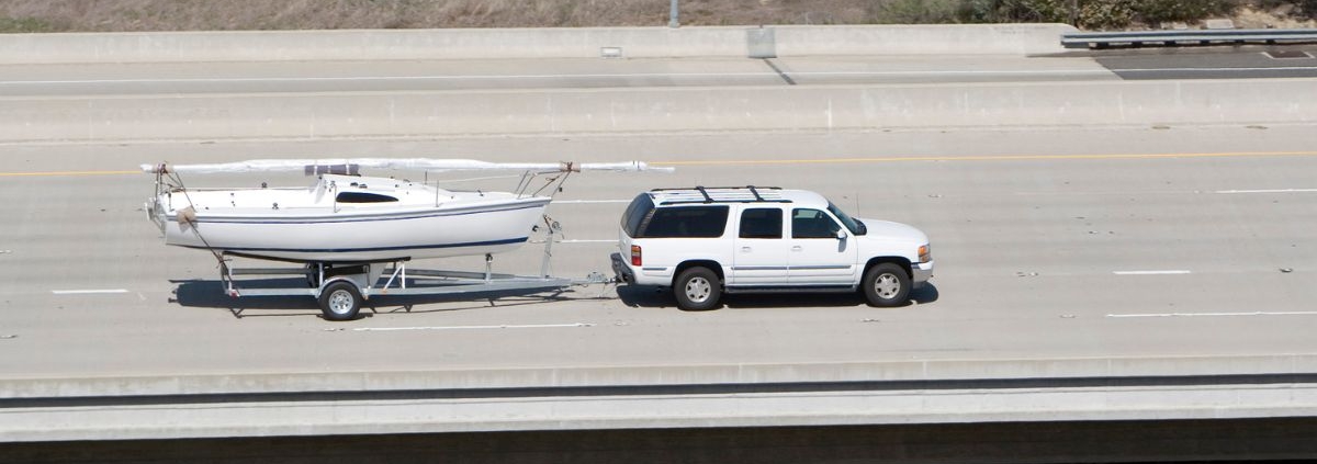 large white SUV towing a white boat on the highway - rocket chip Increasing Power for Towing