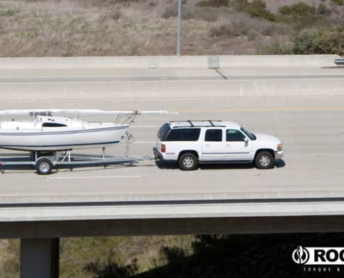 large white SUV towing a white boat on the highway - rocket chip Increasing Power for Towing