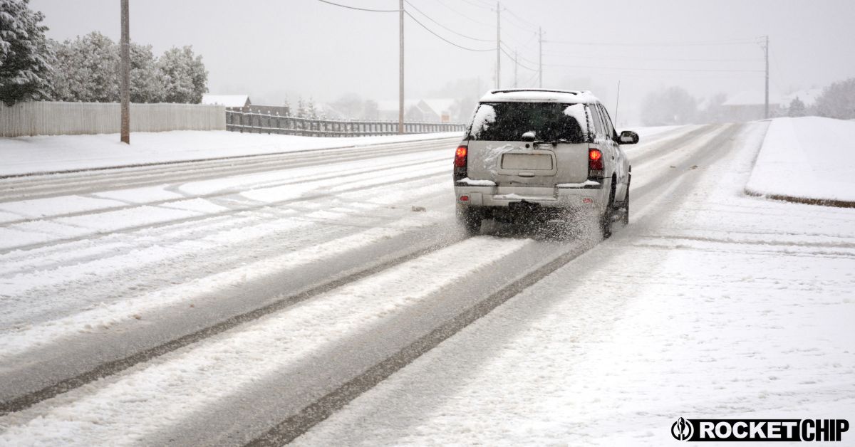 SUV driving through snow covered road - rocket chip vehicle maintenance